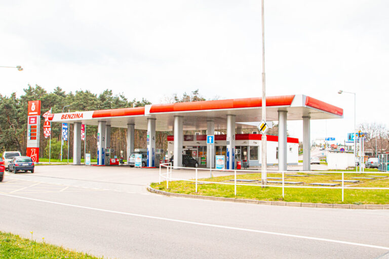 Čerpací stanice Benzina s červeným logem okřídleného koně, cenovým totemem a výdejními stojany