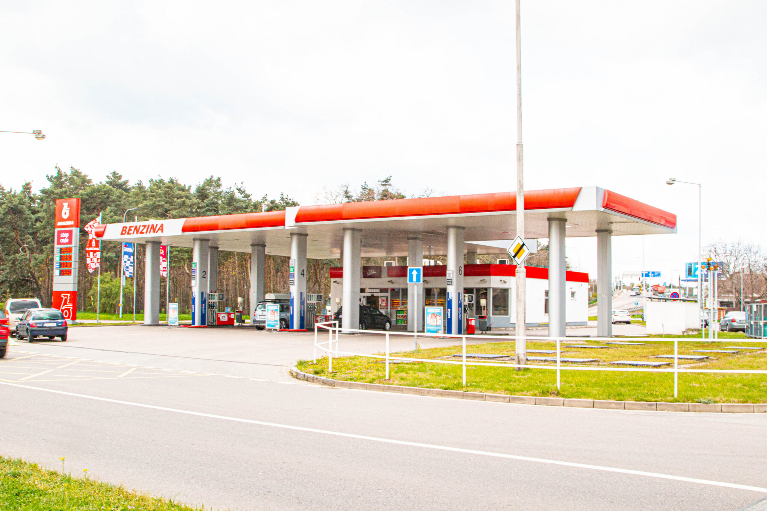 Čerpací stanice Benzina s červeným logem okřídleného koně, cenovým totemem a výdejními stojany