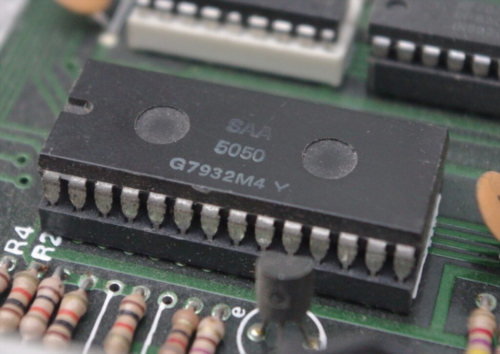 Detail černého integrovaného obvodu Mullard SAA5050 na desce elektroniky