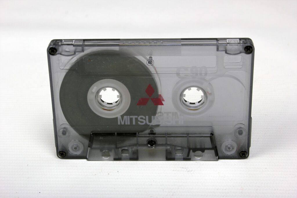Průhledná audiokazeta Mitsubishi C90 s páskem navinutým na levé cívce.