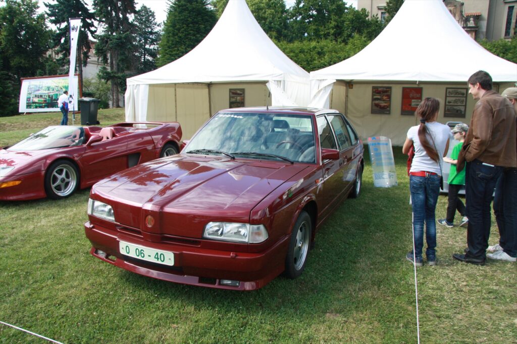 Tmavá reprezentační limuzína Tatra Prezident vystavená na venkovní automobilové přehlídce.