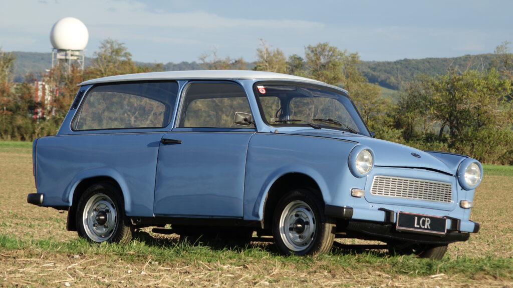 Bílý dvoutaktní automobil Trabant 601 Kombi zaparkovaný na ulici.