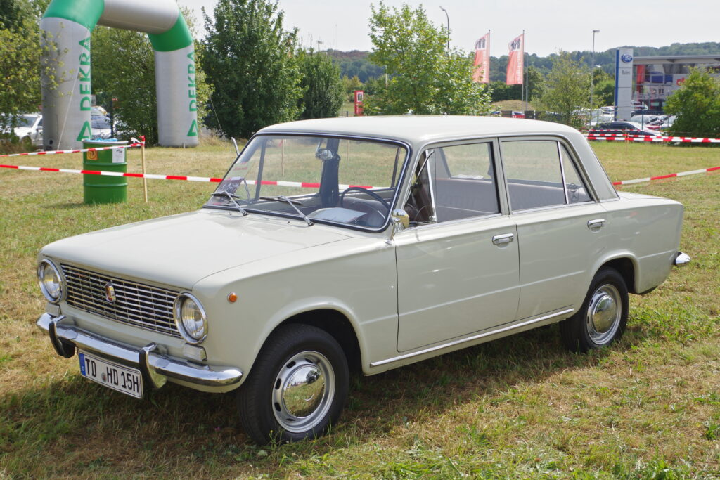 Bílý sedan VAZ 2101 známý jako Žiguli nebo Lada 1200 z bočního pohledu na silnici.