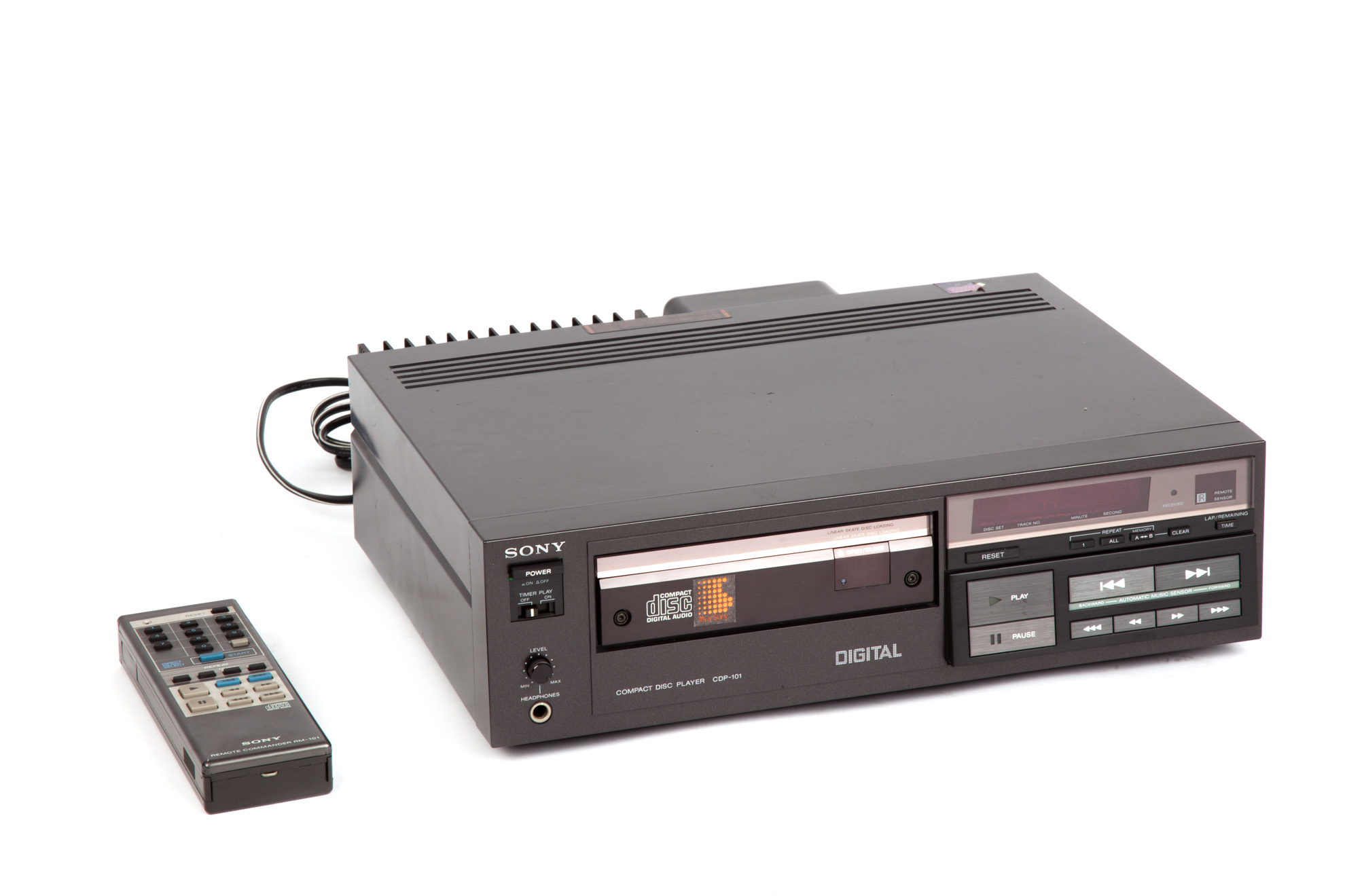Černý přehrávač Sony CDP-101 a dálkový ovladač na bílém pozadí.