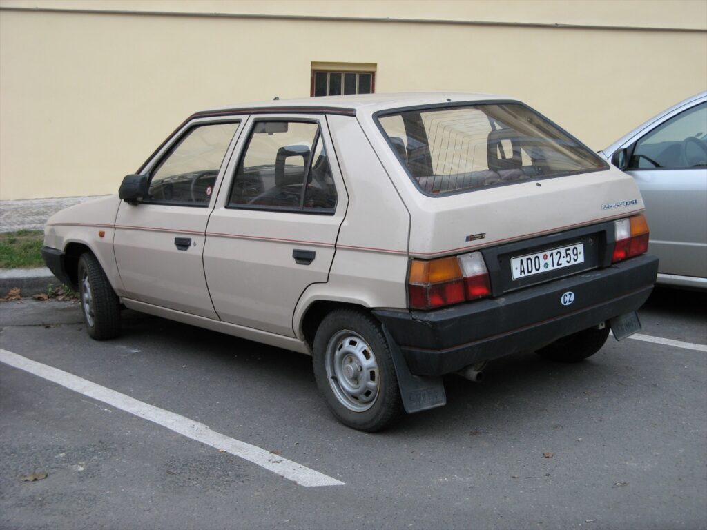 Zadní pohled na hnědý automobil Škoda Favorit 136 L s velkými svítilnami a štítkem modelu na pátých dveřích.