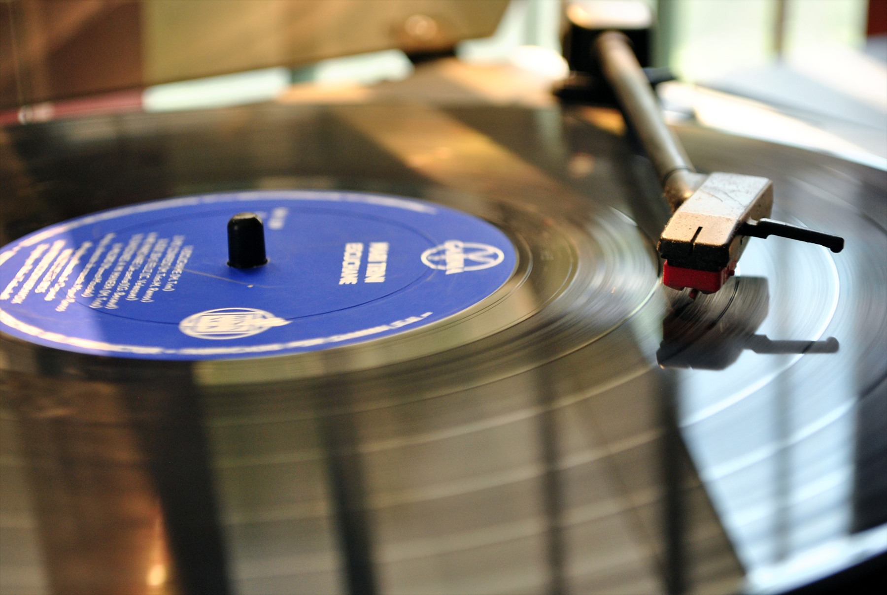 Detailní pohled na černou vinylovou LP desku s mikrodrážkami a středovou papírovou etiketou.