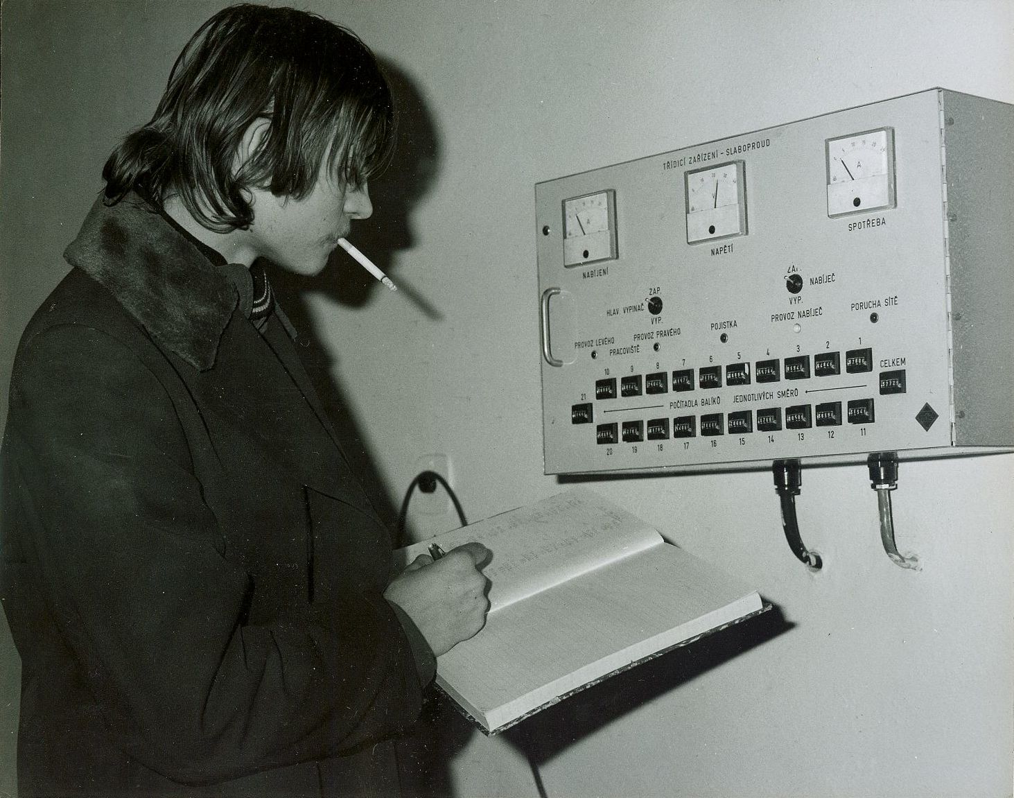 Pracovník s cigaretou u ovládacího panelu poloautomatické linky na třídění balíků