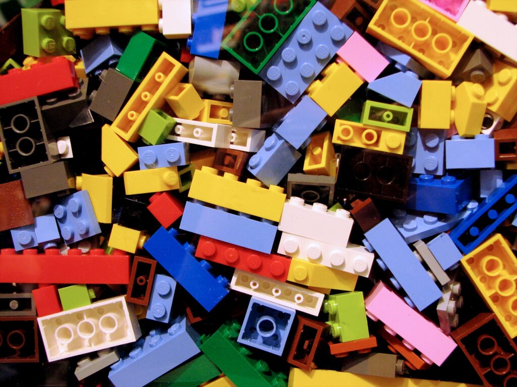 Hromádka různobarevných plastových kostek Lego s typickými výstupky na horní straně.