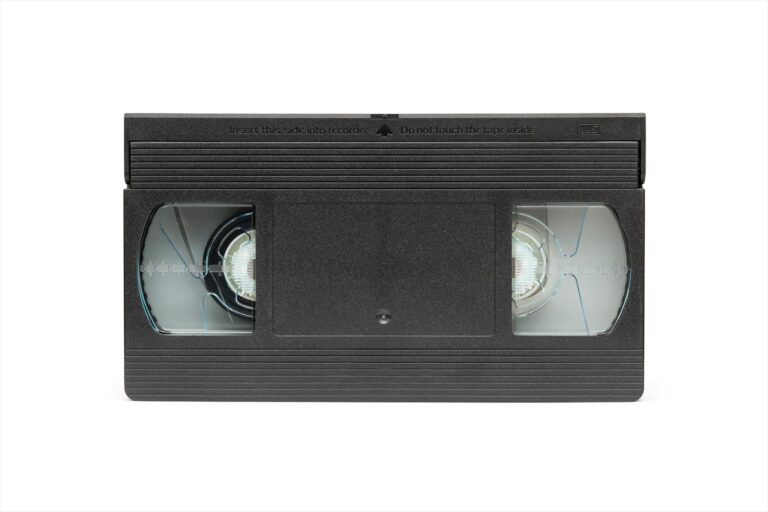 Čelní pohled na černou videokazetu formátu VHS s průhledovými okénky na cívky magnetického pásku.