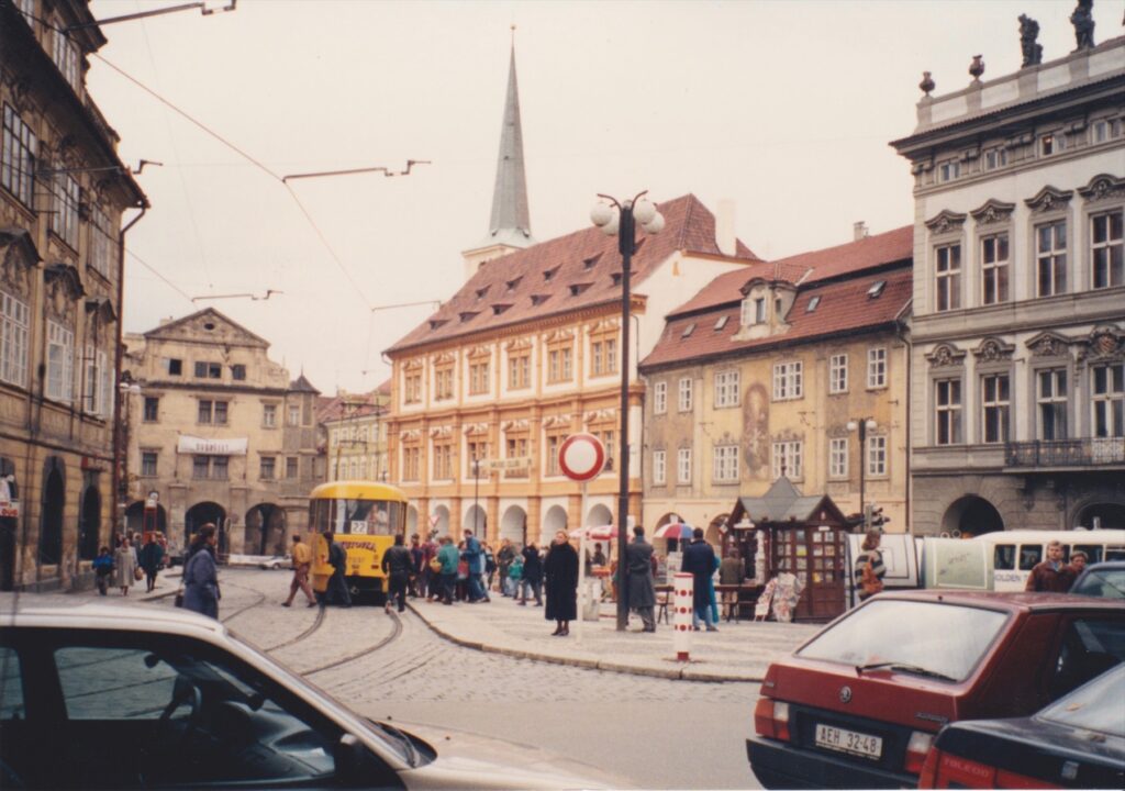 Žlutá tramvaj linky 22 a cestující na Malostranském náměstí v Praze.
