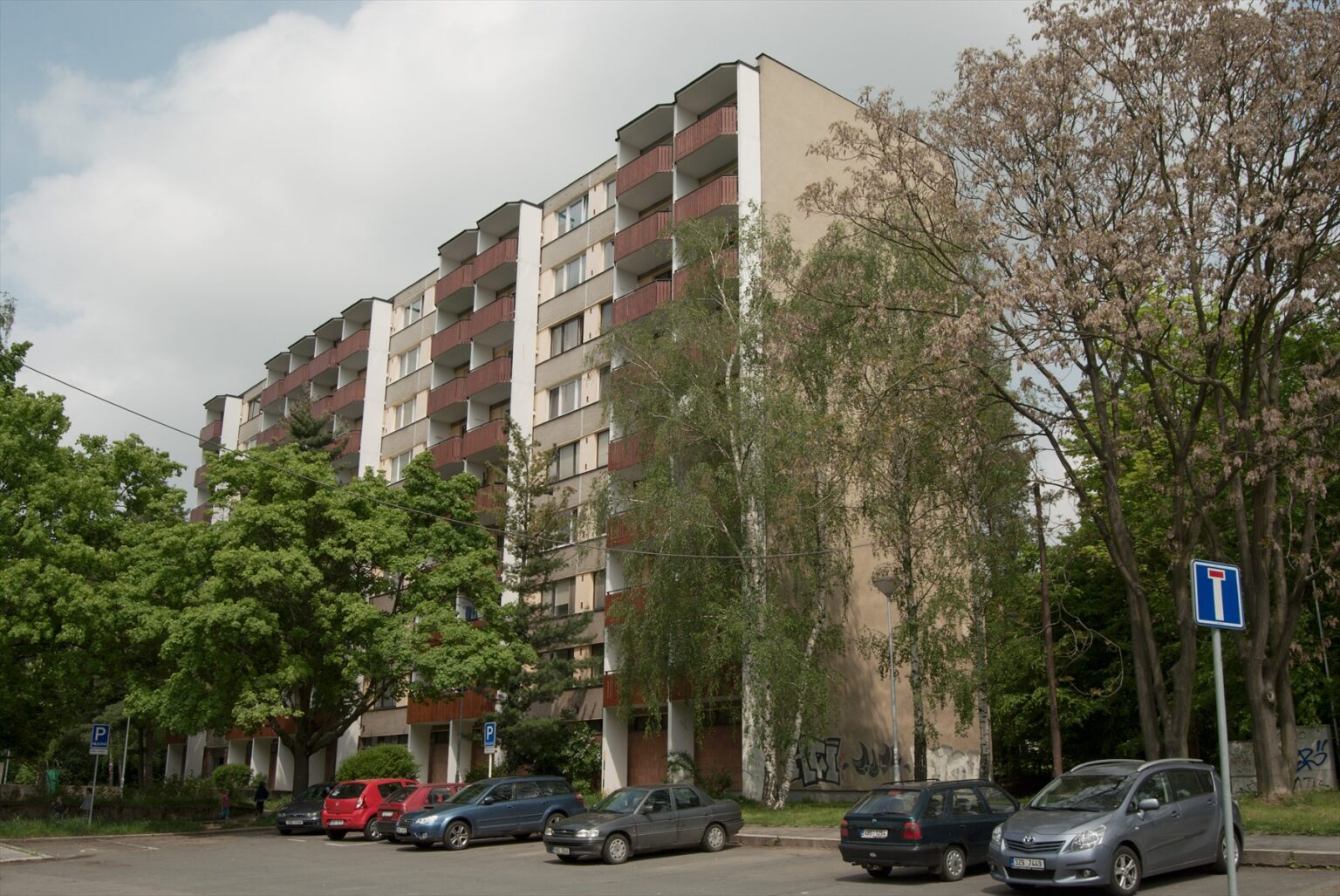 Pohled na modernistický panelový dům v zeleni na sídlišti Lesná v Brně.