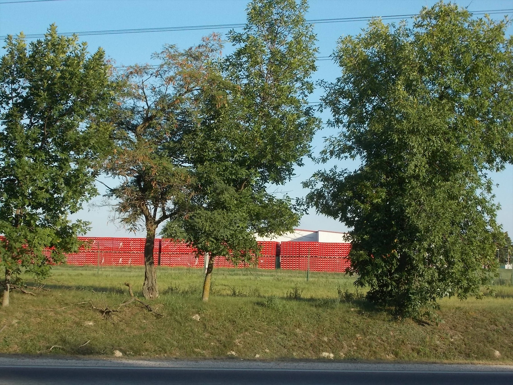 Stohy žlutých plastových přepravek naplněných skleněnými lahvemi ve skladovém areálu stáčírny