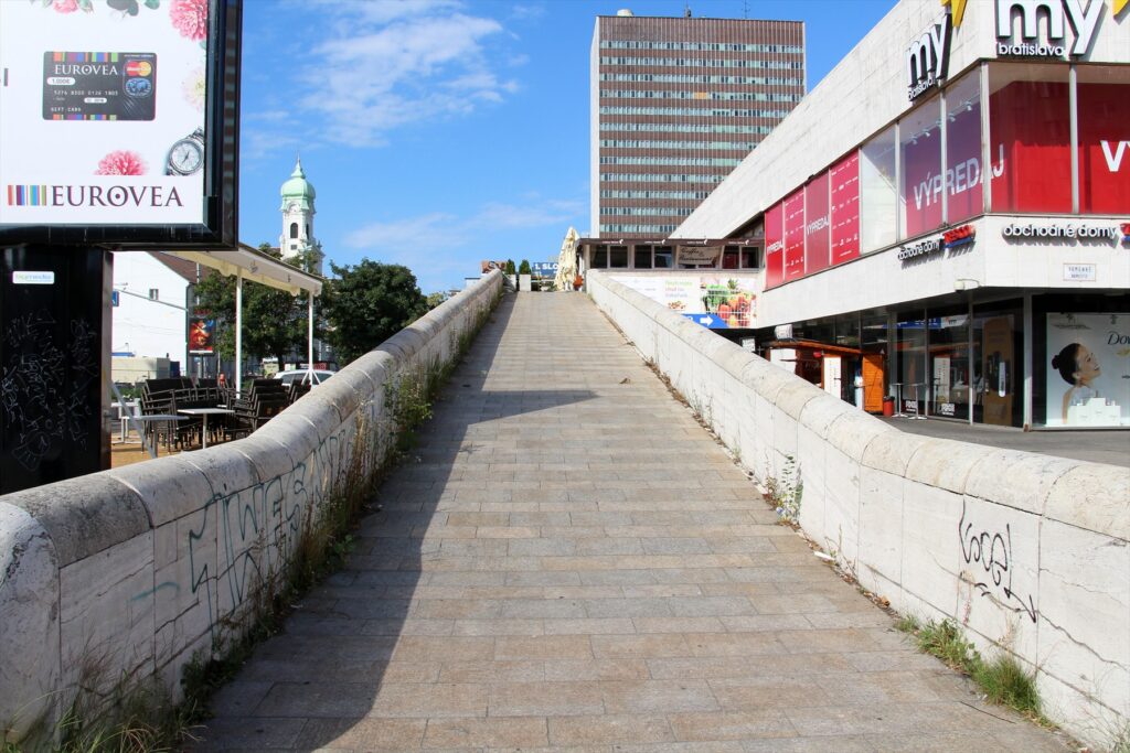 Modernistická budova obchodního domu Prior obložená spišským travertínem a výšková budova Hotelu Kyjev na Kamenném náměstí.