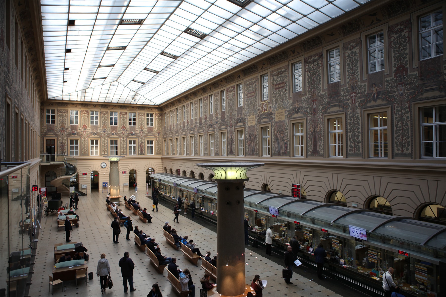 Přepážková hala hlavní pošty v pražské Jindřišské ulici s nástěnnými malbami a čekajícími lidmi