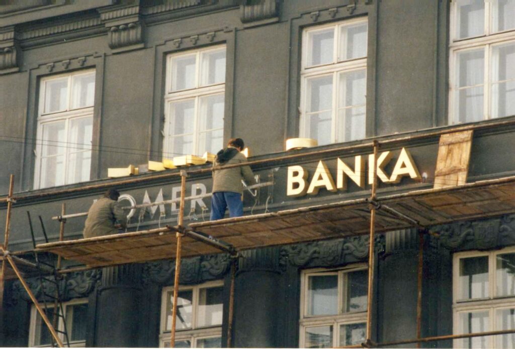 Pobočka banky na náměstí v Novém Jičíně s chodci a automobily v březnu 1992