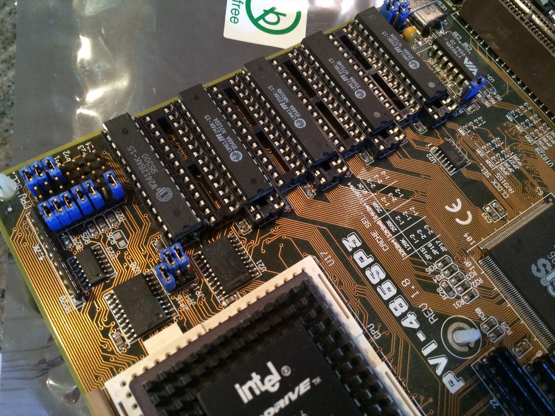Detail základní desky ASUS PVI-486SP3 s paměťovými čipy, modrými propojkami a procesorem Intel.