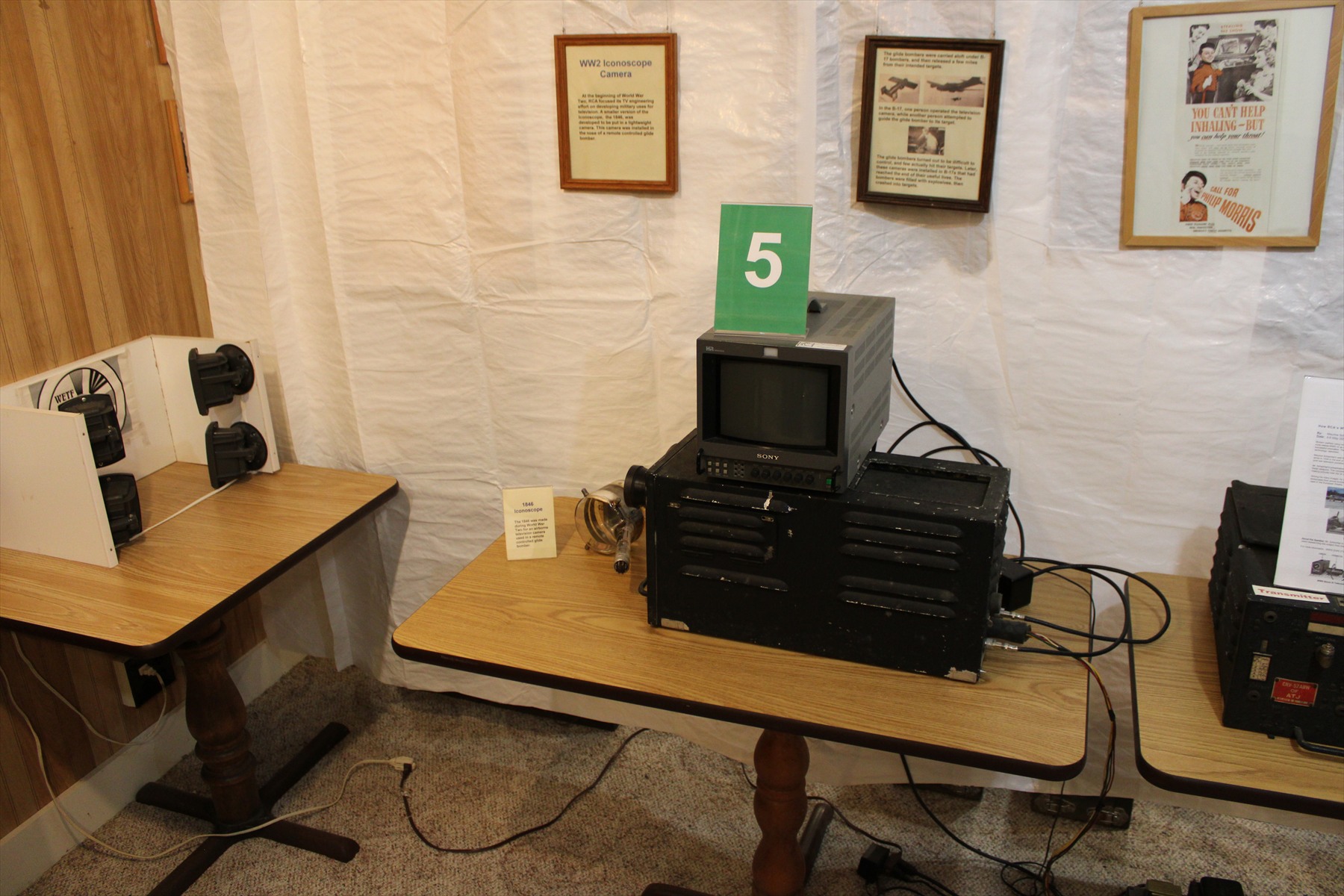 Černá historická televizní kamera s monitorem a zkušební předlohou vlevo v muzejní expozici.