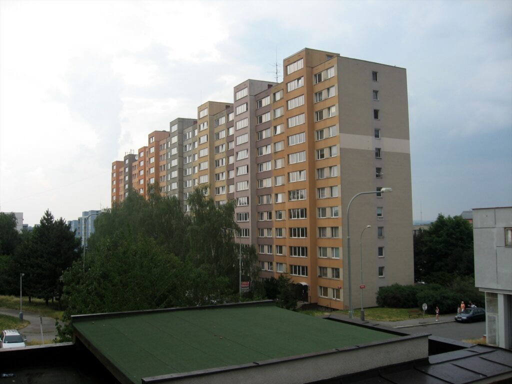 Řada panelových obytných domů s balkony a lodžiemi na pražském sídlišti.