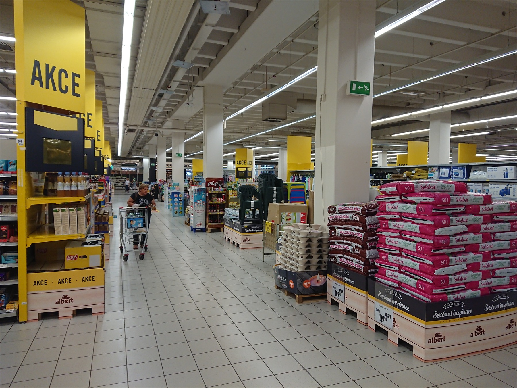 Ulička hypermarketu Albert s regály, zbožím a nákupními vozíky