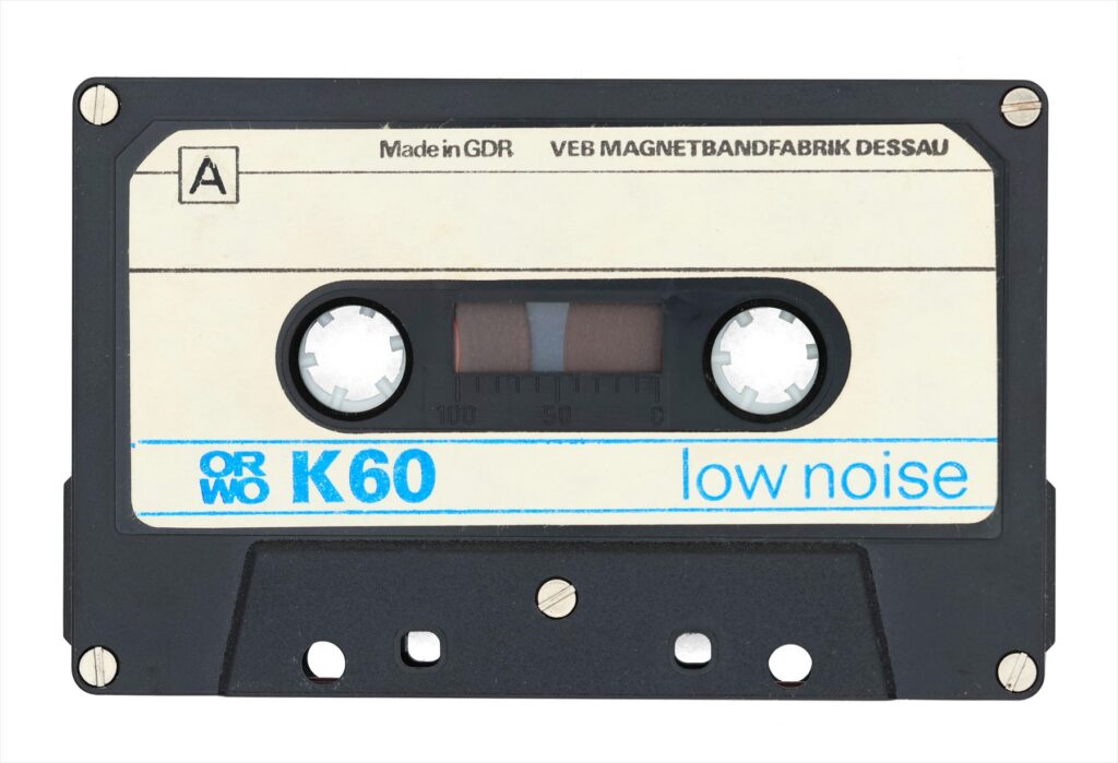 Dvě kompaktní audiokazety značky ORWO v průhledných plastových krabičkách používané pro záznam zvuku a počítačových dat.