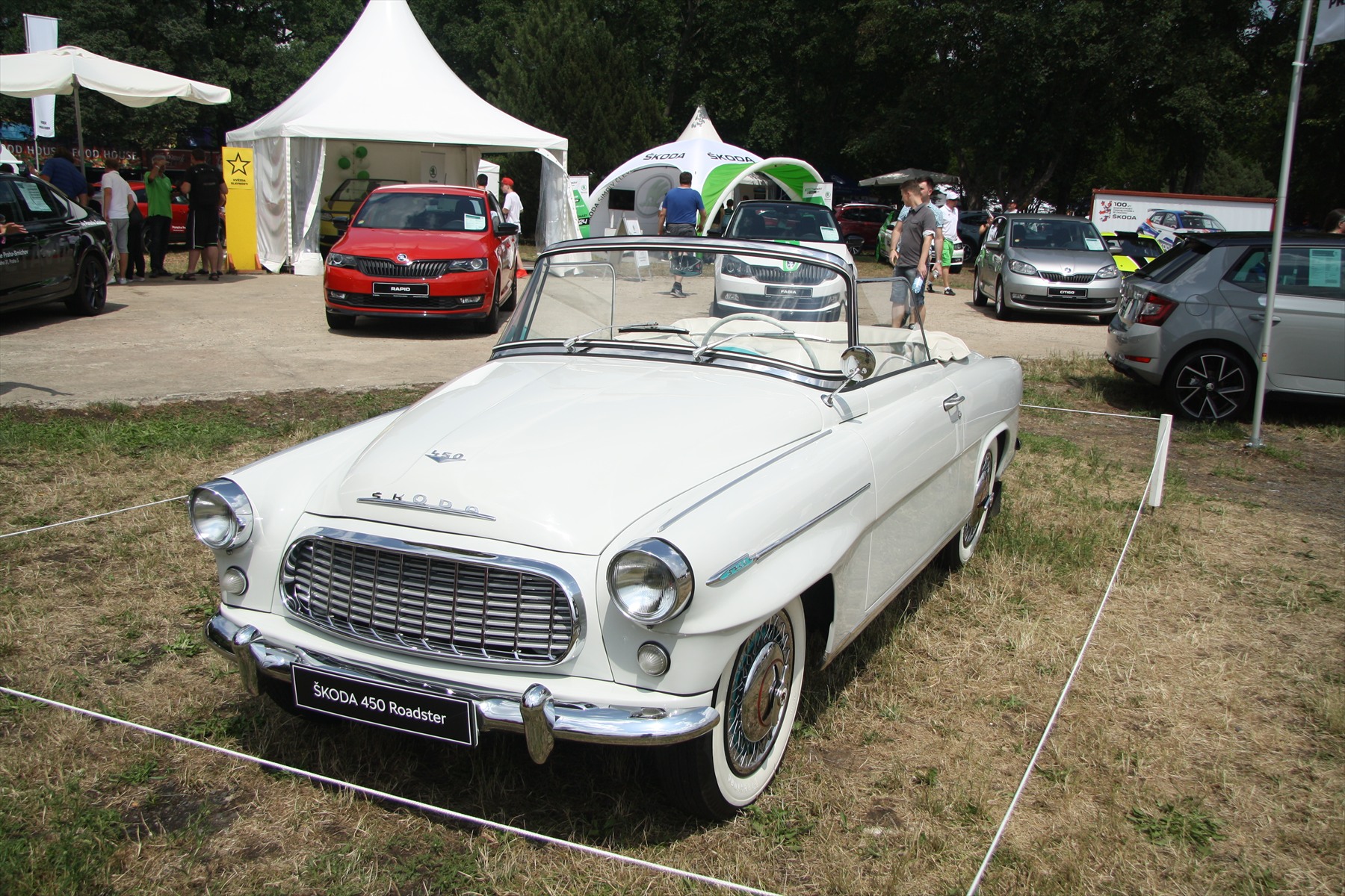 Červený dvoudveřový otevřený automobil Škoda 450 se staženou střechou na výstavní ploše.