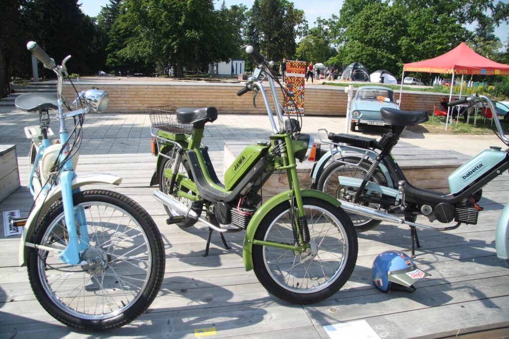 Pohled na žlutý moped Babetta 210 vystavený na trávníku v profilovém záběru.