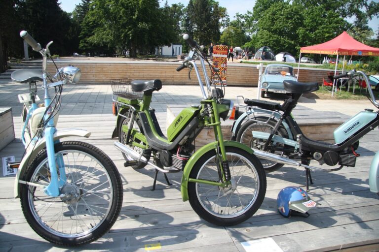 Pohled na žlutý moped Babetta 210 vystavený na trávníku v profilovém záběru.