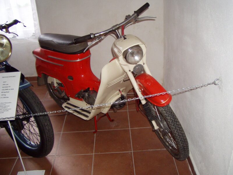 Červeno-bílý malý motocykl Jawa 50 typ 20 s revmaplechy a stupátky.