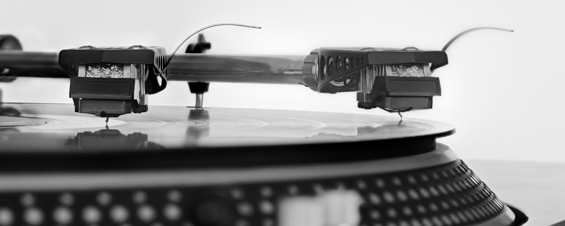 Detailní záběr hrotu gramofonové přenosky v drážce rotujícího černého vinylu