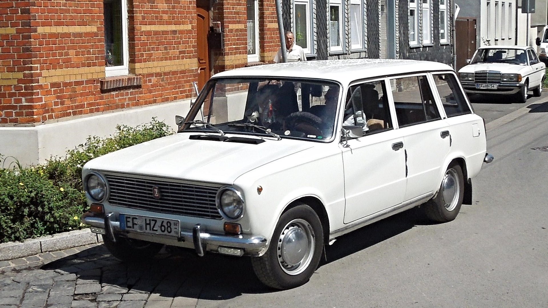 Bílý automobil Lada 1200 Žiguli při jízdě po venkovské silnici