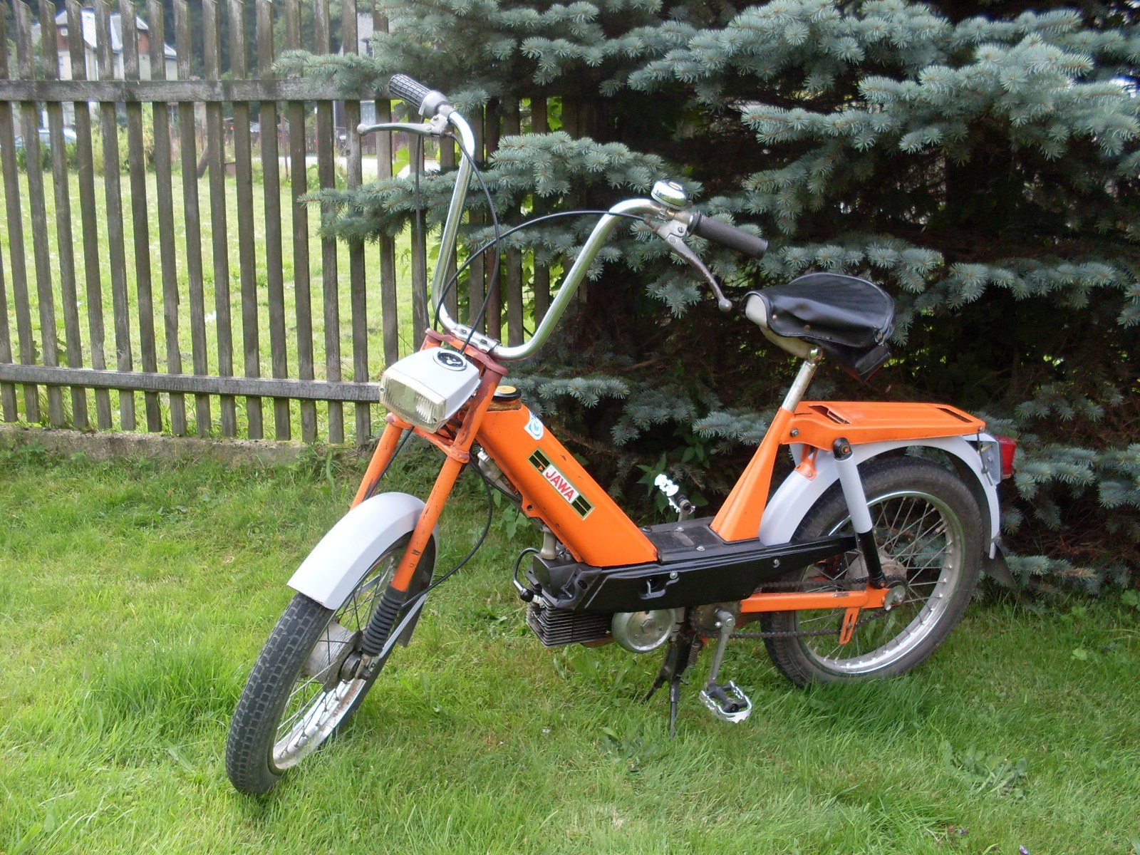 Červený moped Babetta 207 stojící před domem s viditelným motorem a šlapadly.
