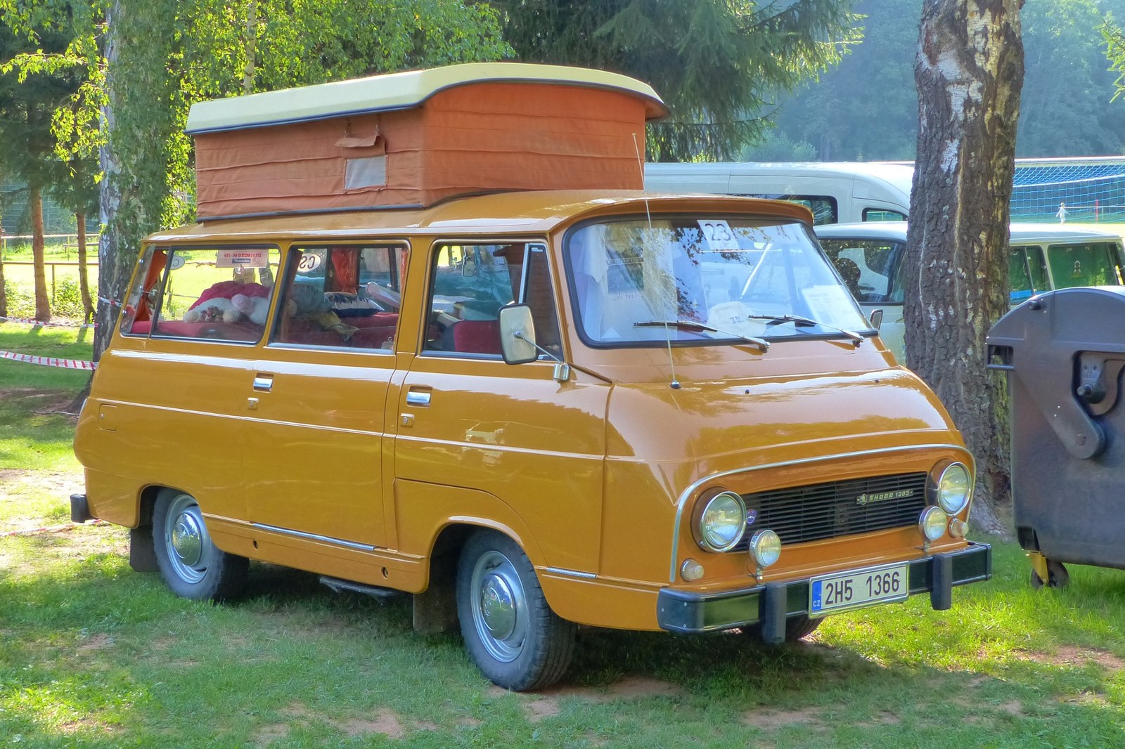 Žlutý obytný automobil Škoda 1203 CAMP s vyklopenou stanovou střechou a kempingovým vybavením.