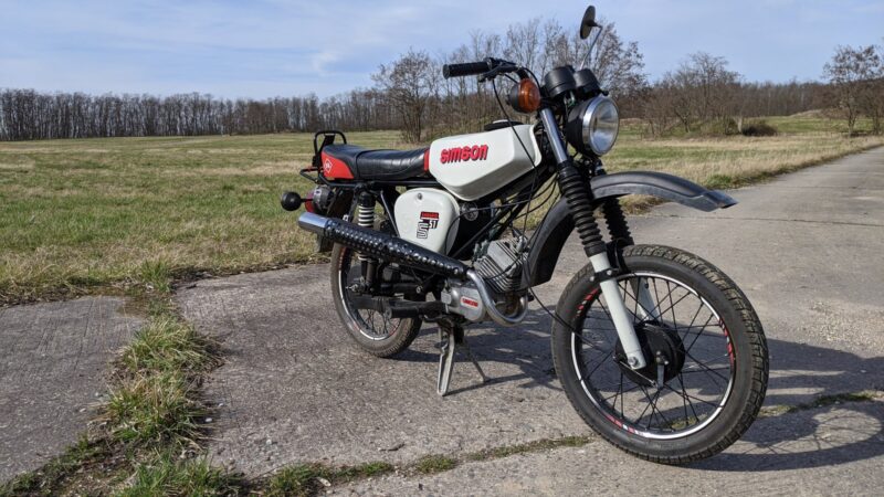 Zrenovovaný stříbrný moped Simson S51 Enduro se zvednutým výfukem a terénním vzorkem pneumatik