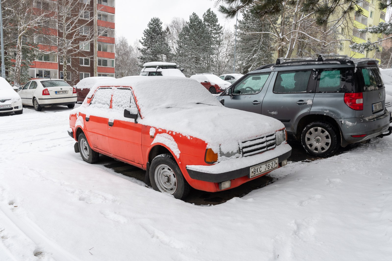 Bílý osobní automobil Škoda sto dvacet L zaparkovaný na ulici